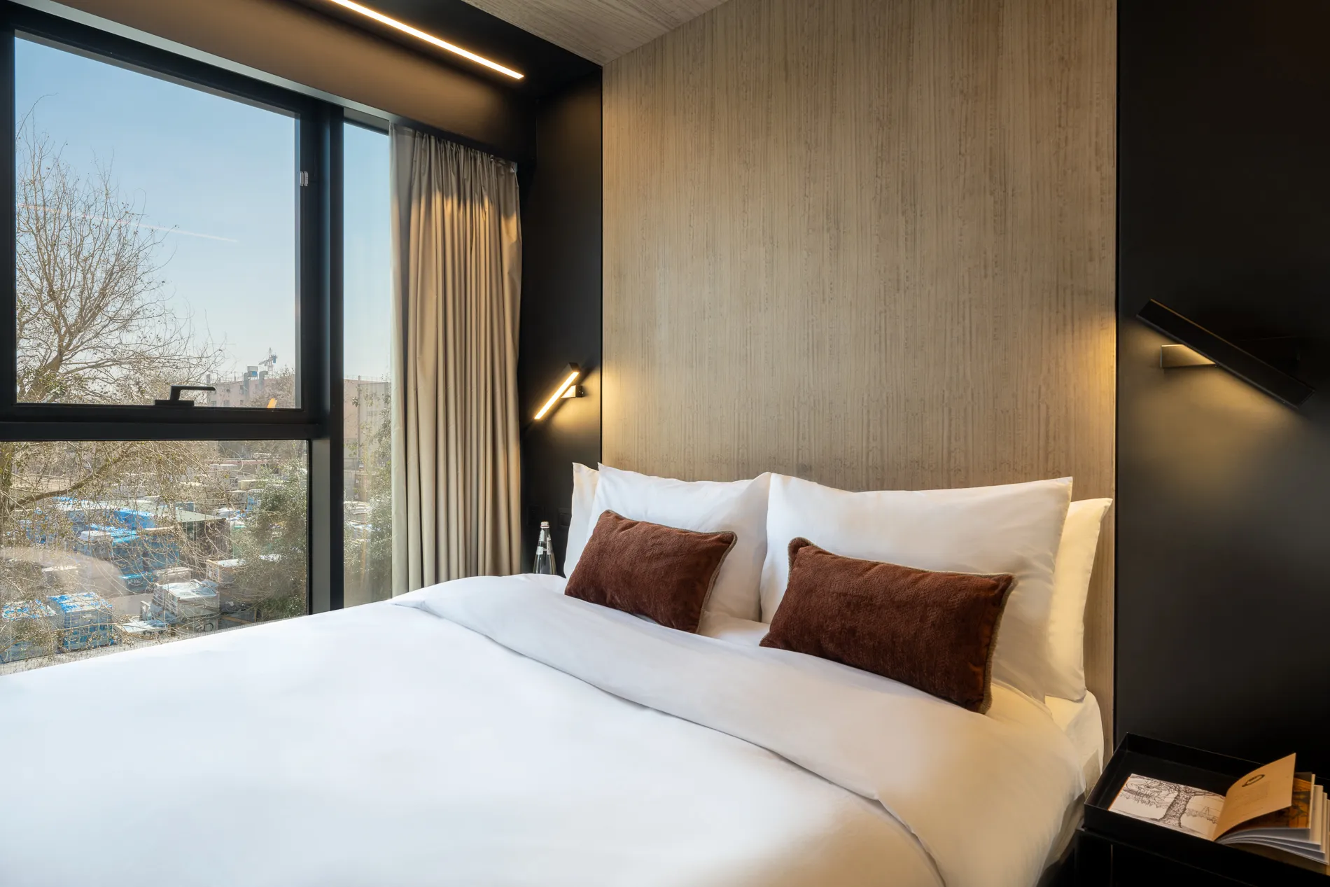 Comfortable bedroom in a master Bat Yam apartment, featuring a plush bed and a large window that fills the space with natural light.