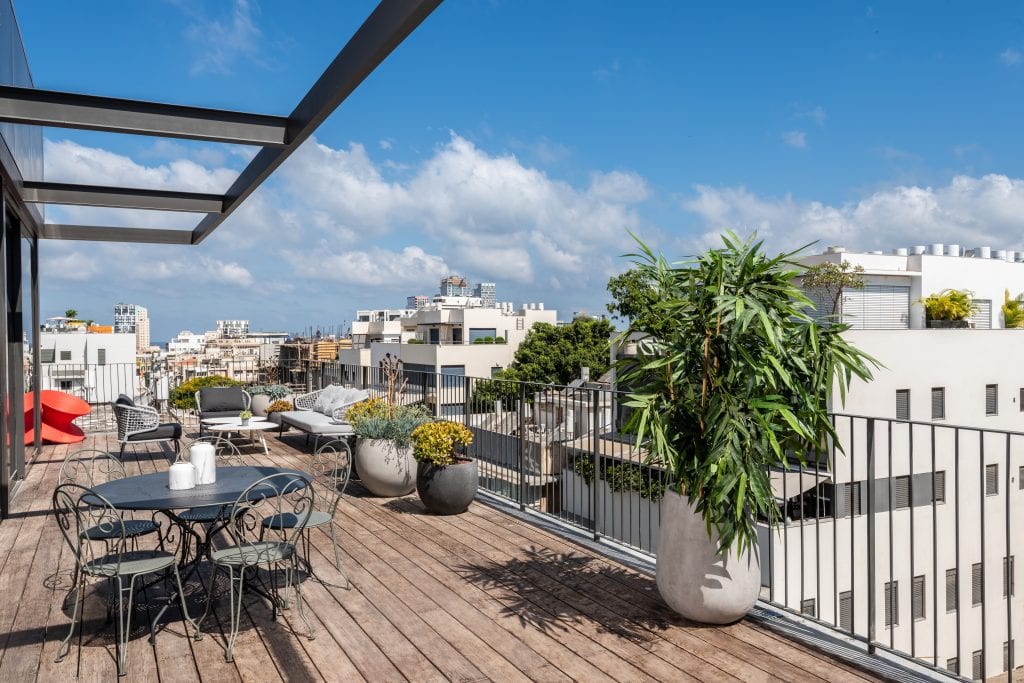 Modern rooftop terrace in the Four-Bedroom Penthouse at master Shenkin Tel Aviv, featuring open-air seating and panoramic city views.