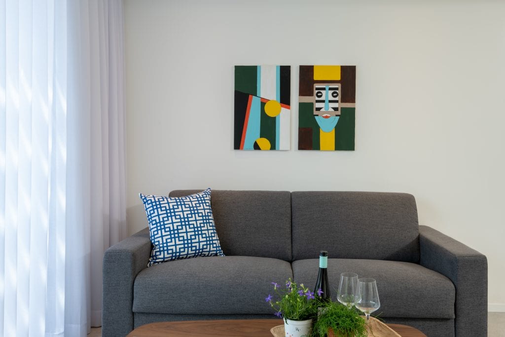 Cozy and stylish living area in the Four-Bedroom Apartment at master Shenkin Tel Aviv, featuring a plush sofa for a comfortable stay.