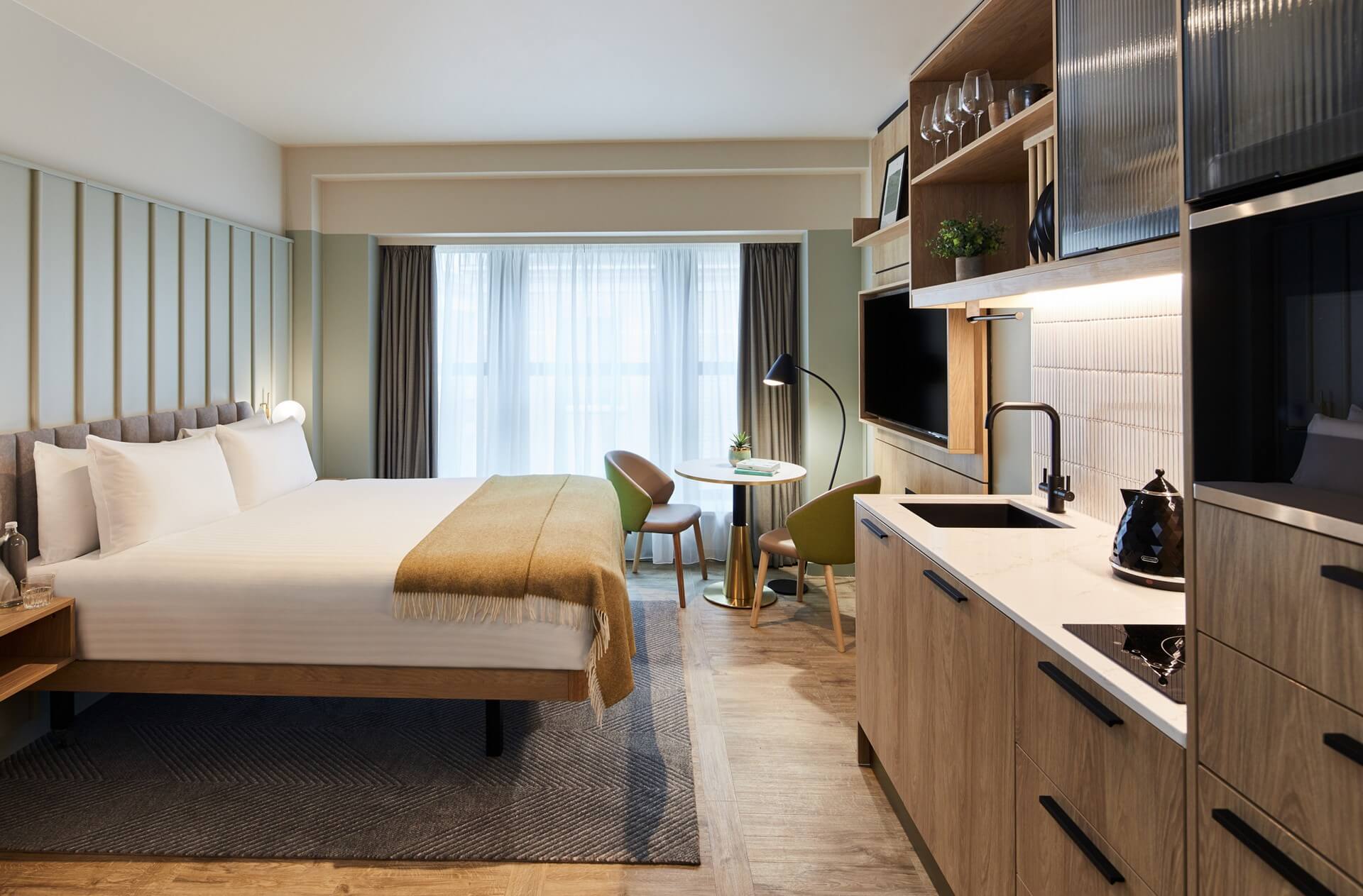 Spacious Studio at master St. Paul’s London, featuring a cozy bed, modern kitchenette, and a dining area with a table and two chairs.