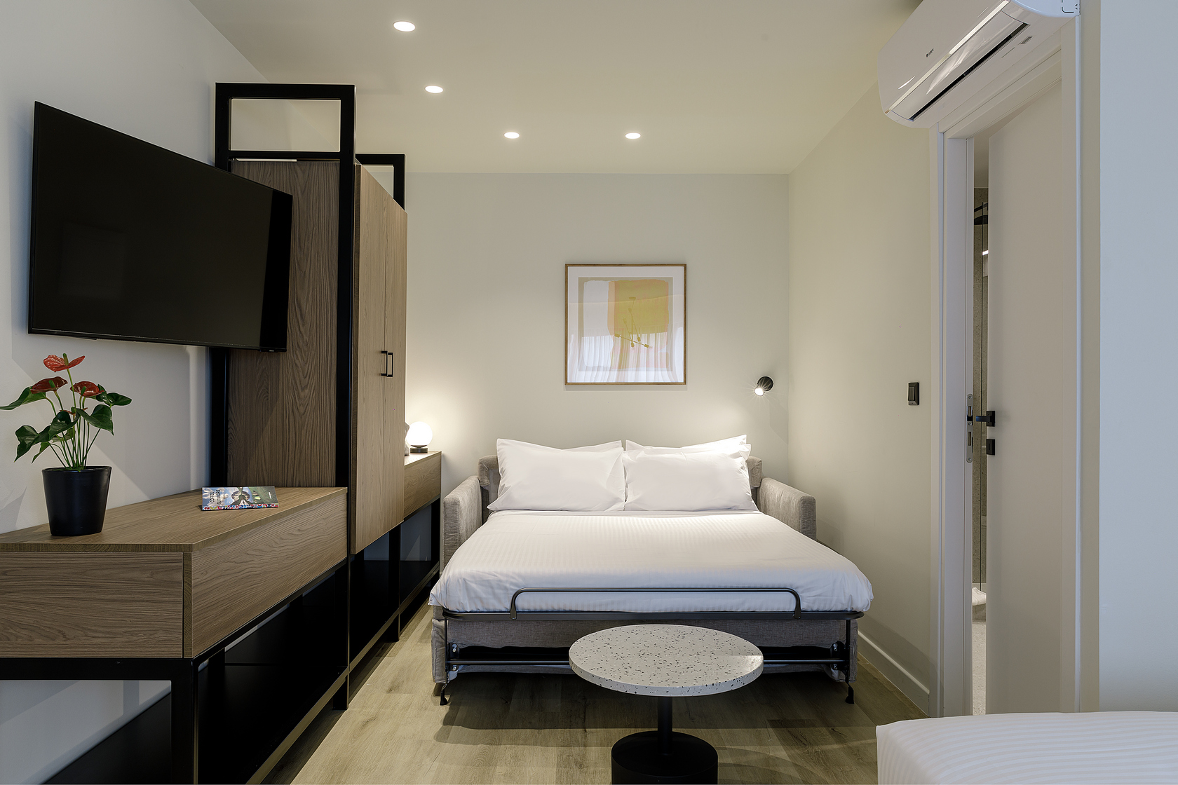 Plush bed in the Studio with Sofa Bed at master Plaka Athens, complemented by soft lighting and elegant decor.