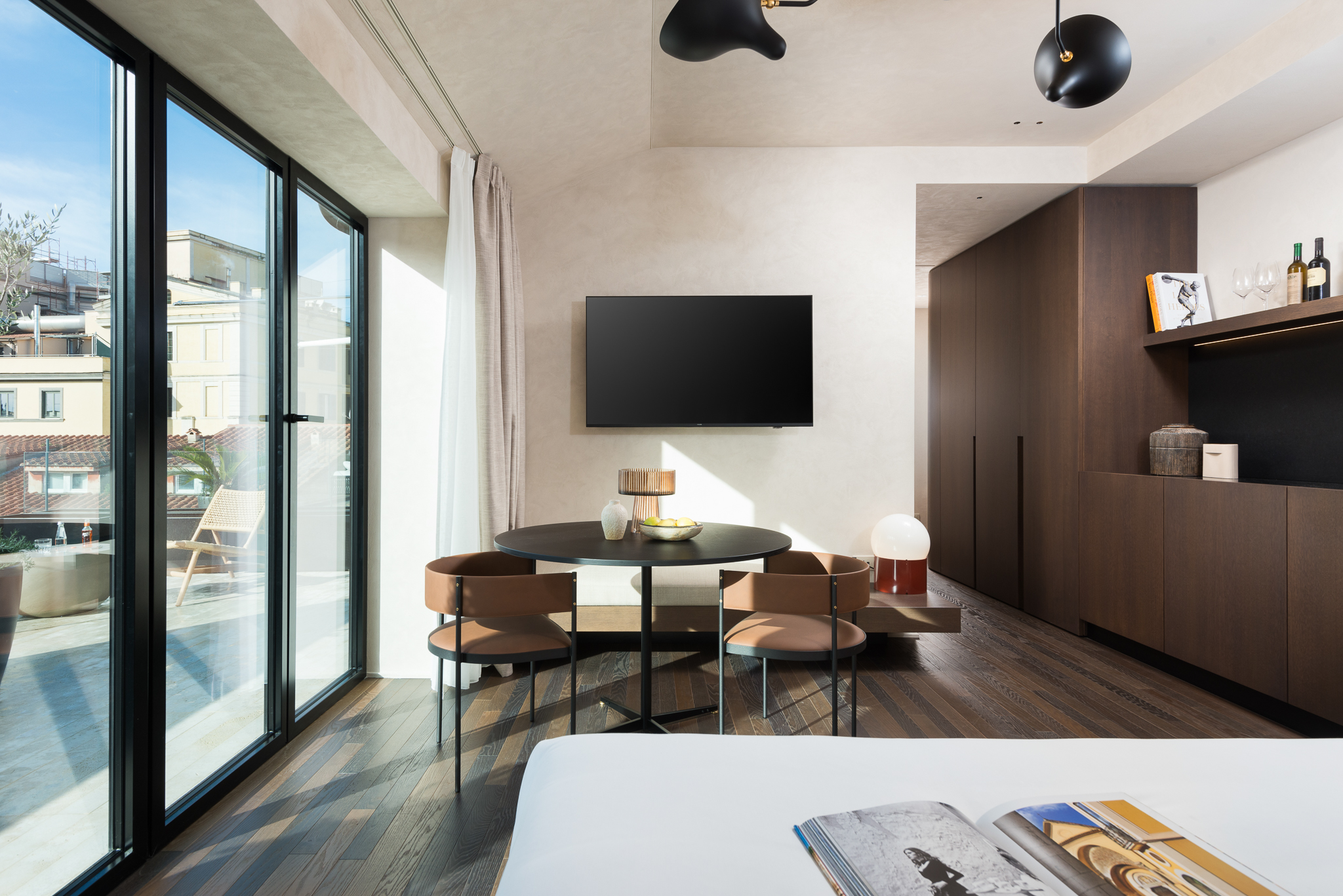 Spacious bedroom in the Three-Bedroom Penthouse at master Trevi Rome, featuring a cozy bed, a modern dining table, and a balcony with city views.