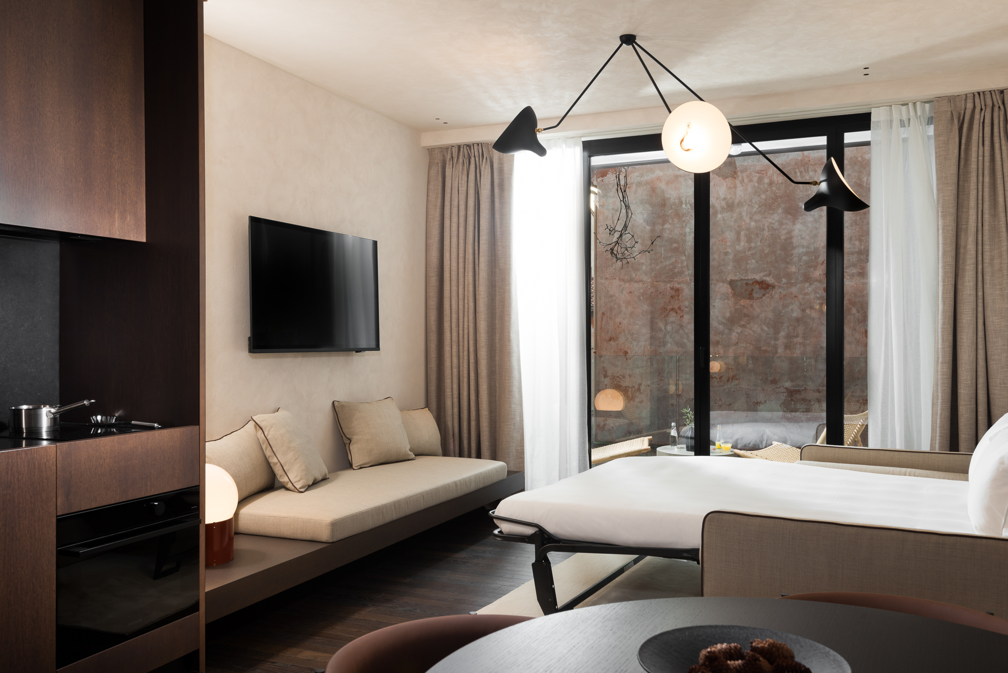 Modern living area in the Large Studio with Balcony at master Trevi Rome, featuring an open sofa bed and direct access to a private balcony with city views.