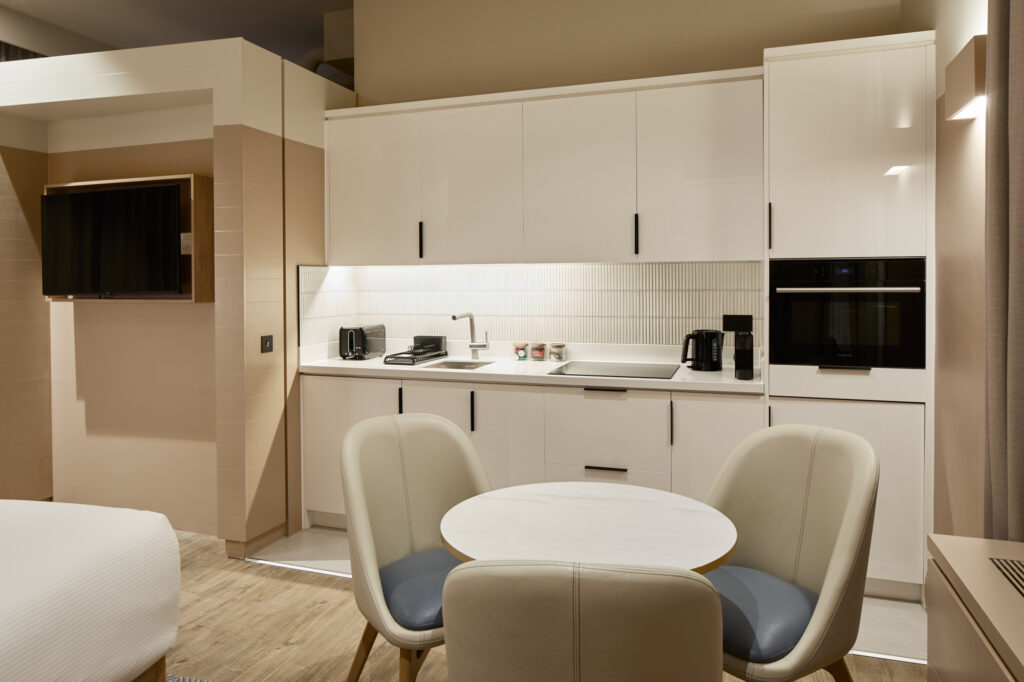 Modern kitchenette and small dining area with round table and two chairs in the studio with sofa bed at master Cannon London.