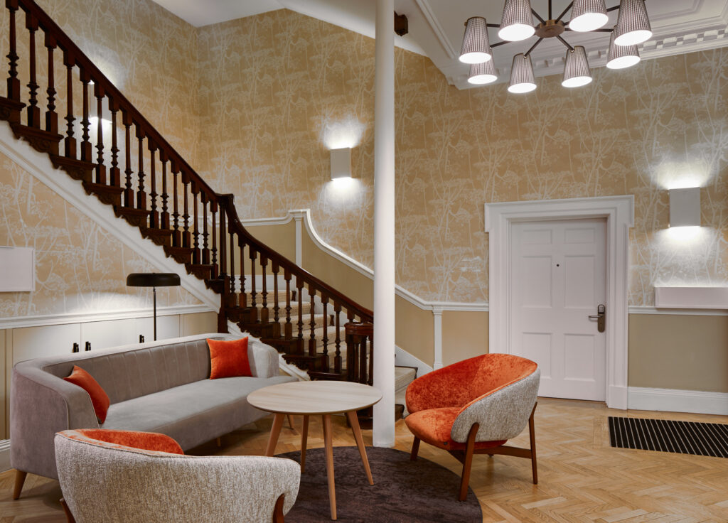 Sophisticated lobby area at master Cannon London apartments with a stylish seating arrangement, contemporary decor, and a wooden staircase leading upstairs