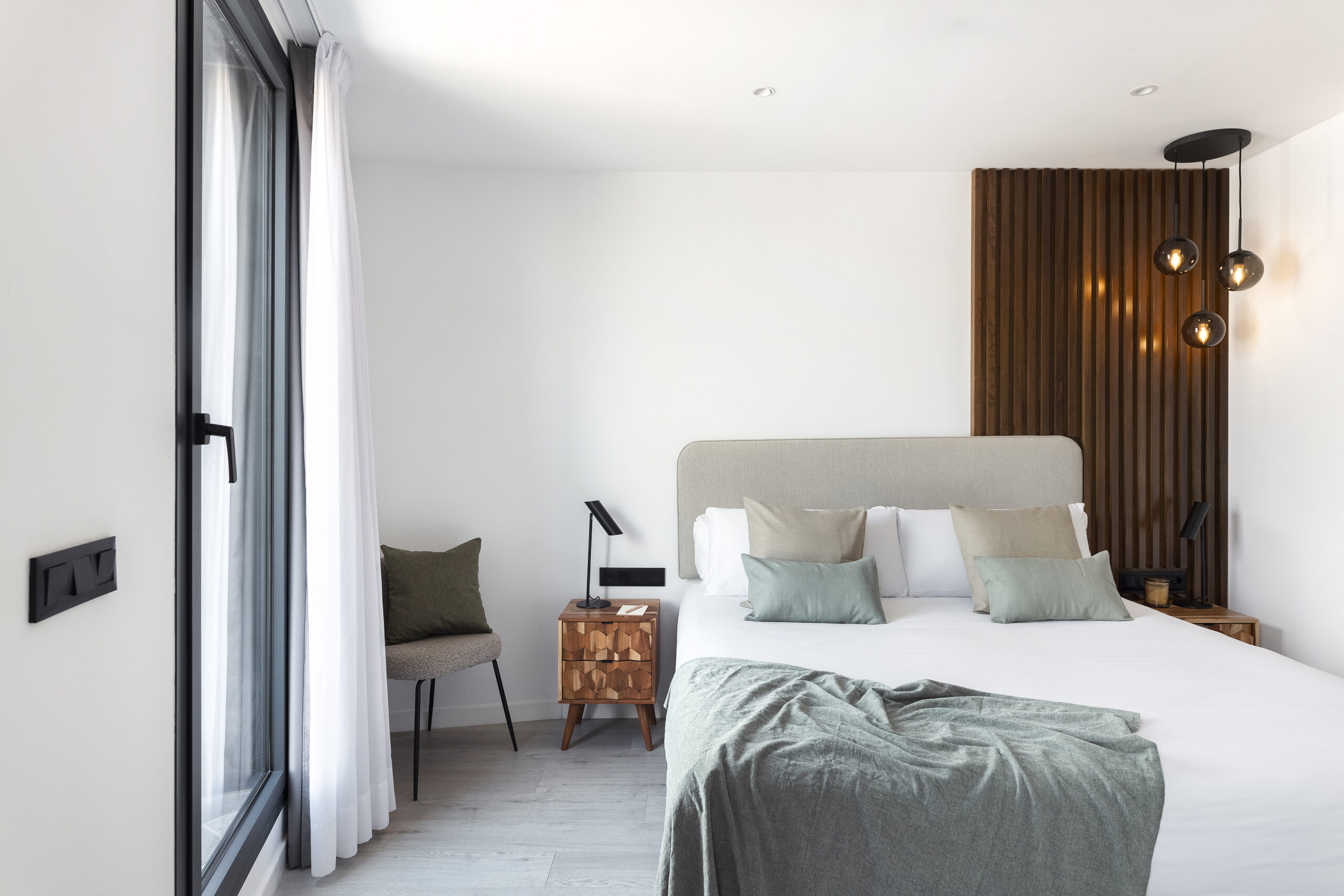 Stylish bedroom at master La Rambla Barcelona featuring modern design, soft-toned bedding, and floor-to-ceiling windows.