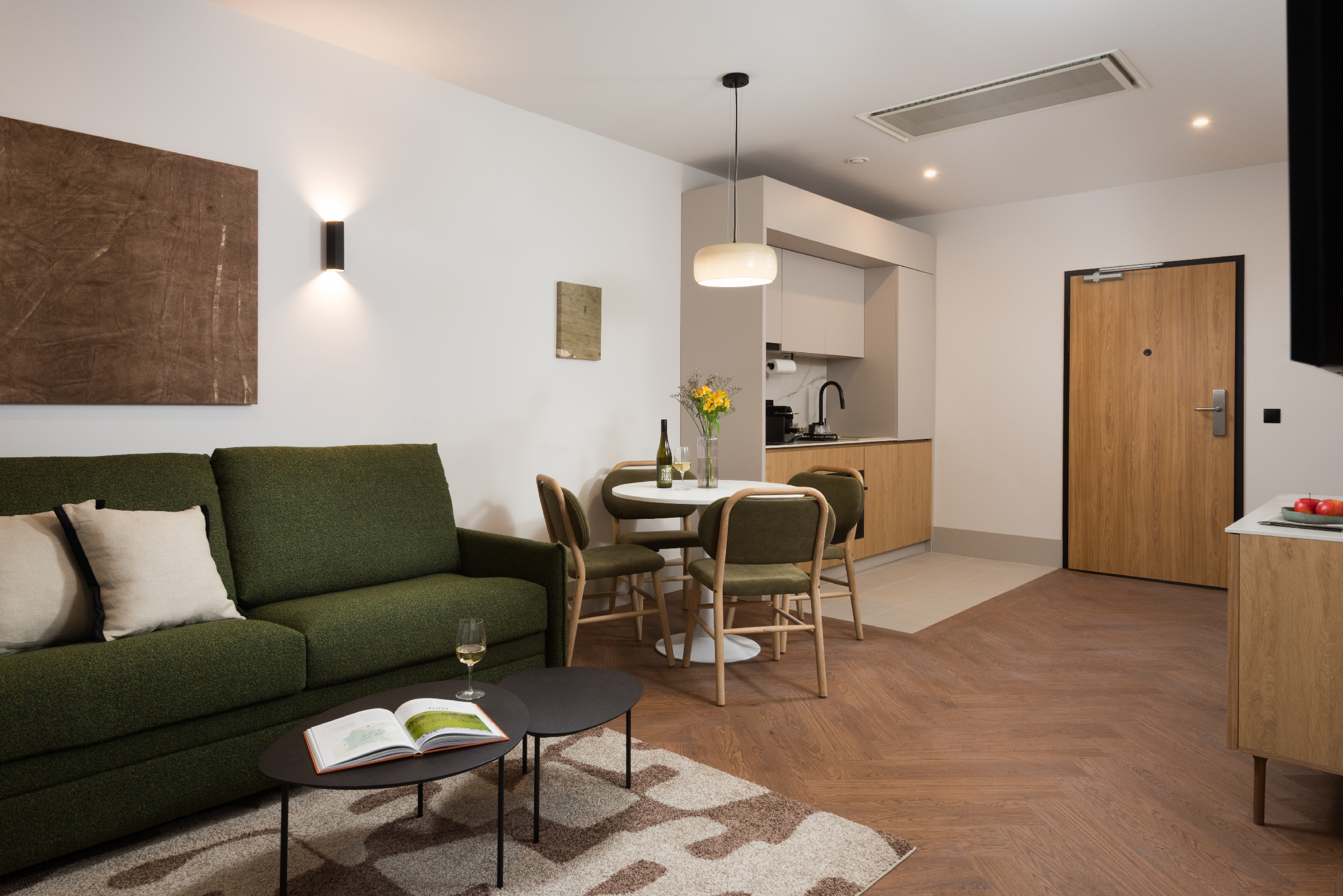 Open-plan living and dining area in the Family Apartment at master Wola Warsaw, including seating area, dining table, and kitchenette.