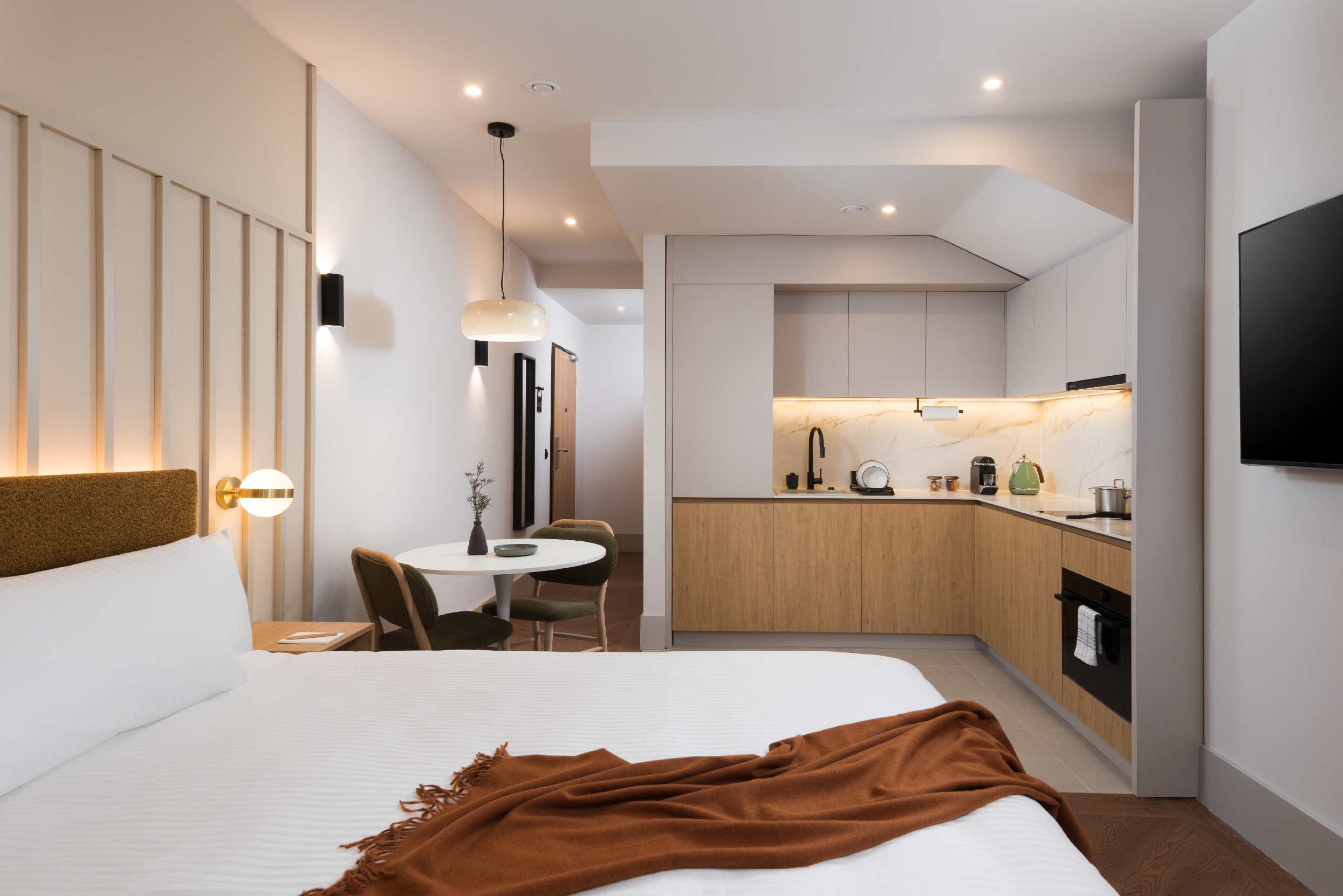 Family Apartment bedroom at master Wola Warsaw overlooking the kitchenette and dining area, showcasing a bright, functional open-plan layout.