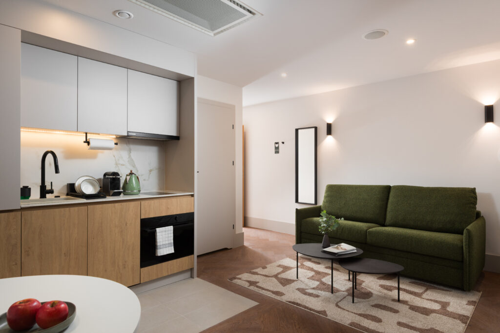 Studio apartment kitchenette and living area at master Wola Serviced Apartments with sofa and coffee table