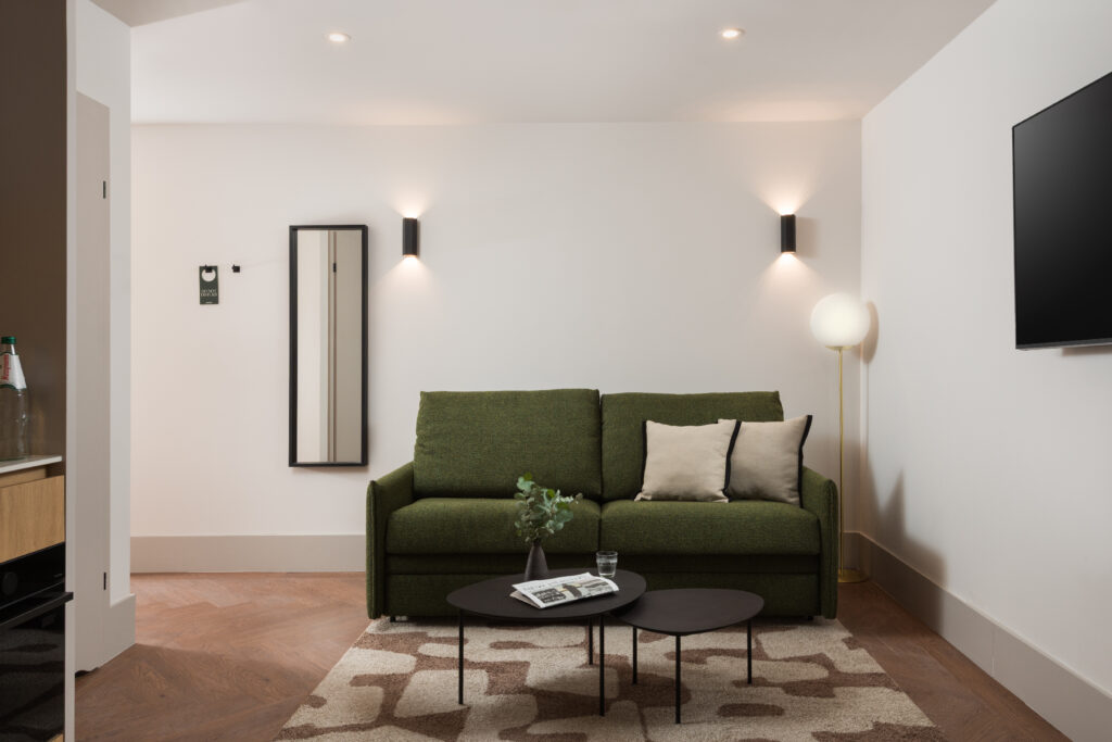 Comfortable seating area in a studio apartment at master Wola Serviced Apartments with green sofa and coffee table