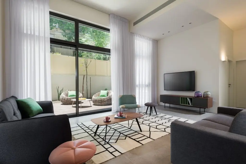 Bright and inviting living area in the Five-Bedroom Duplex Garden at master Shenkin Tel Aviv, seamlessly connecting to the lush garden through glass doors.