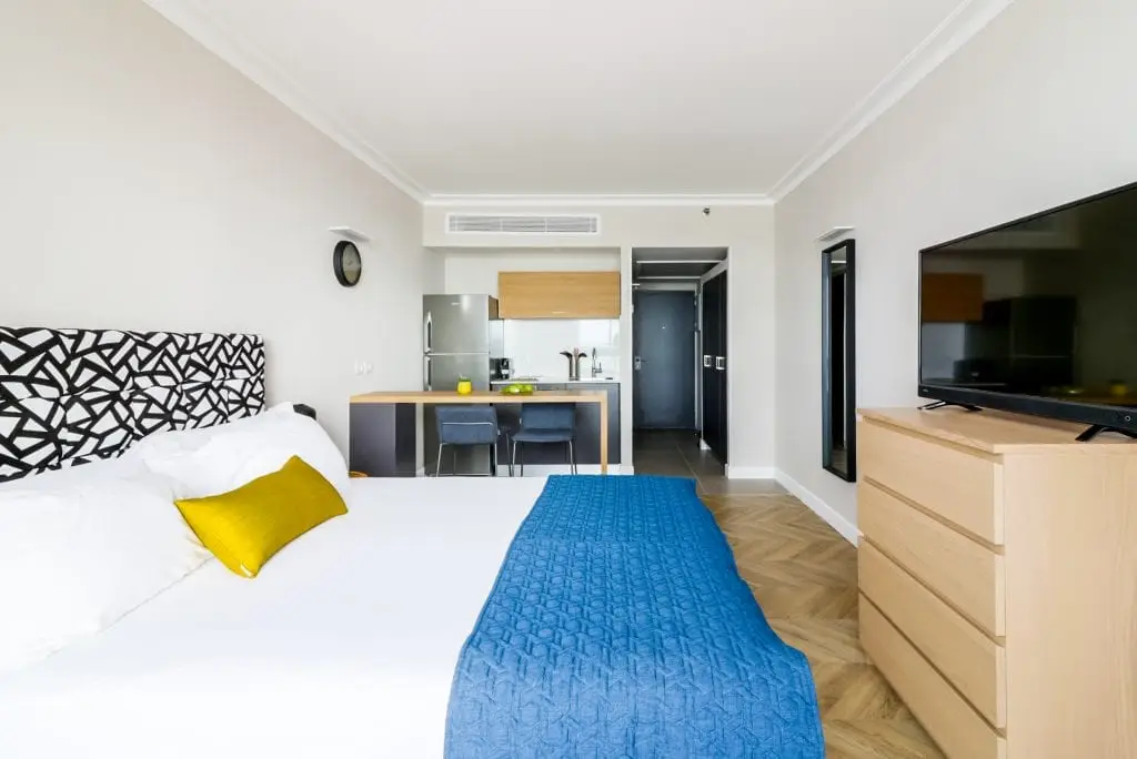 Well-appointed studio at master Haifa, showcasing a cozy bed and a functional kitchenette in a modern open-plan layout.
