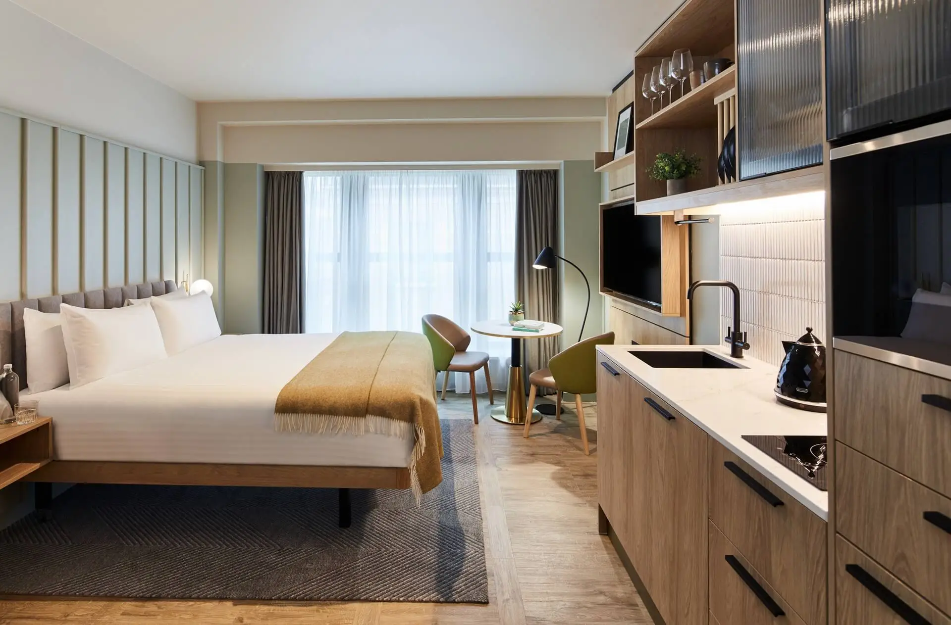 Spacious Studio at master St. Paul’s London, featuring a cozy bed, modern kitchenette, and a dining area with a table and two chairs.