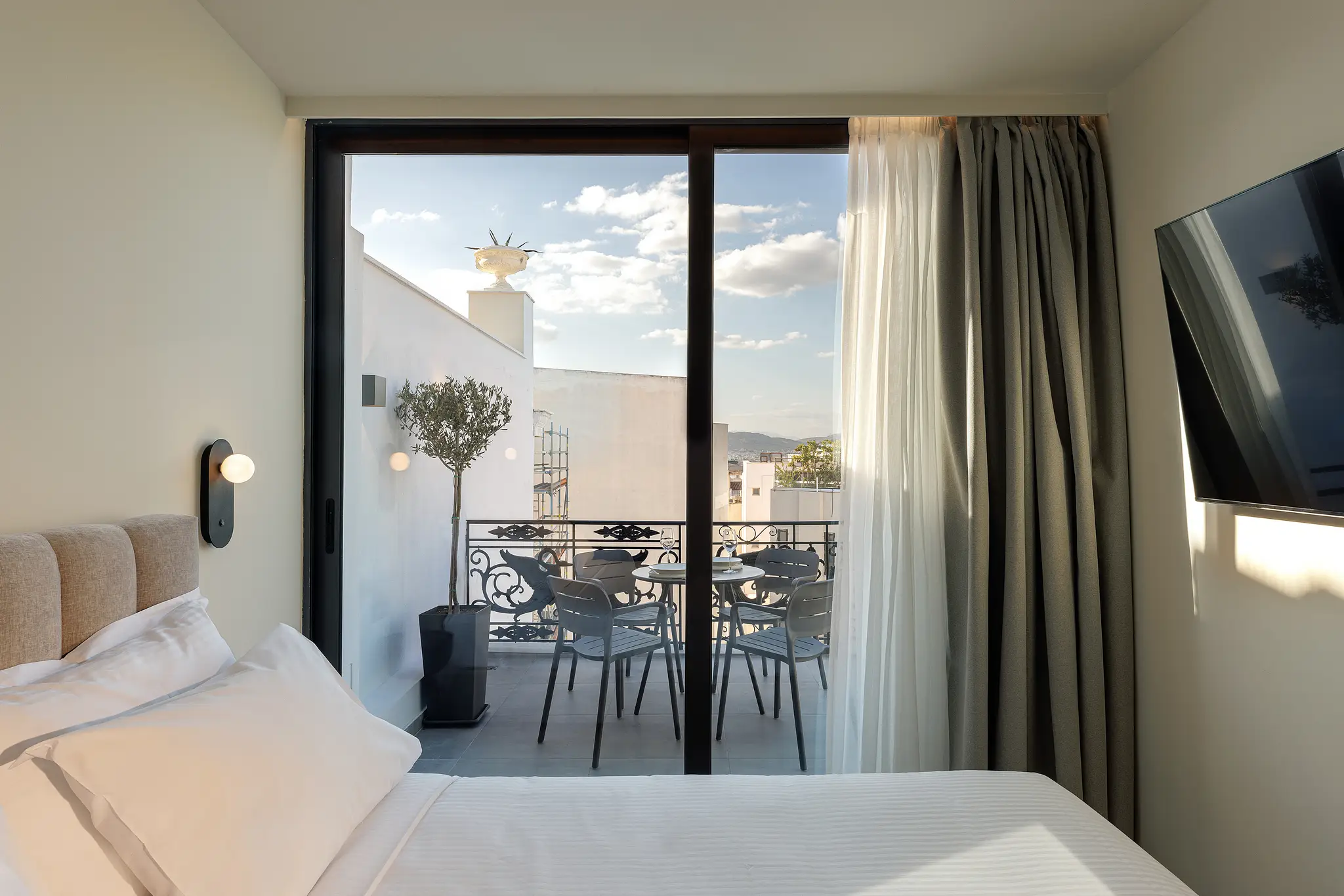 Bright bedroom in the Family Room at master Plaka Athens, offering a comfortable bed and access to a private balcony with city views.