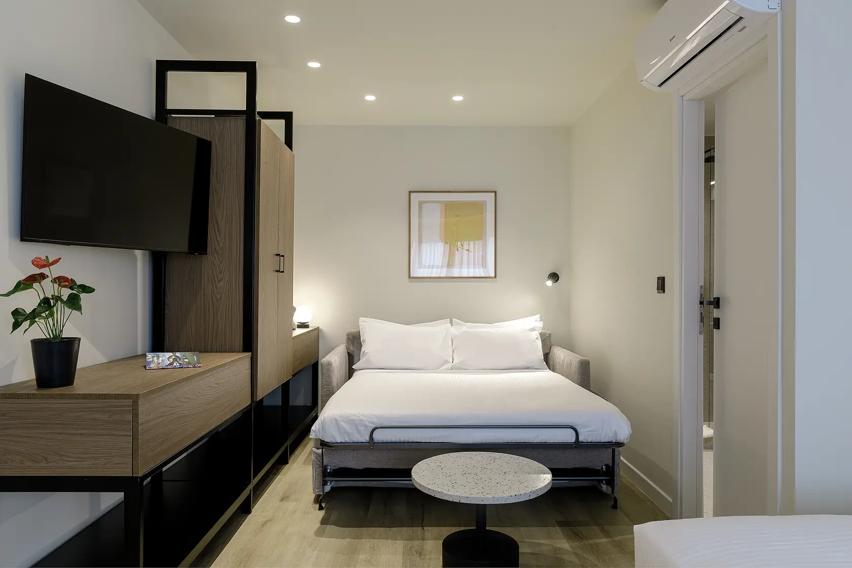 Plush bed in the Studio with Sofa Bed at master Plaka Athens, complemented by soft lighting and elegant decor.