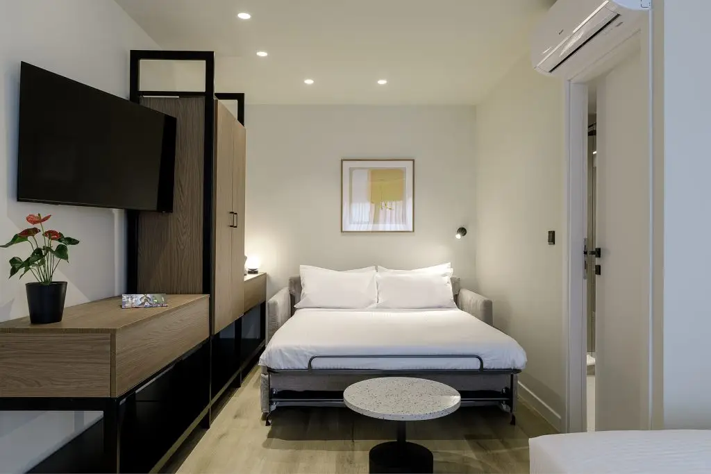 Comfortable bed in the Family Apartment at master Plaka Athens, surrounded by warm lighting and elegant decor for a relaxing stay