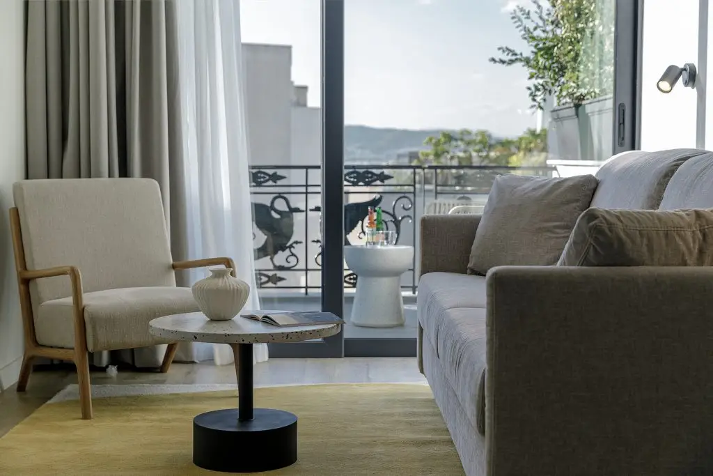 Spacious living area in the Family Room at master Plaka Athens, featuring a cozy sofa and direct access to a private balcony.