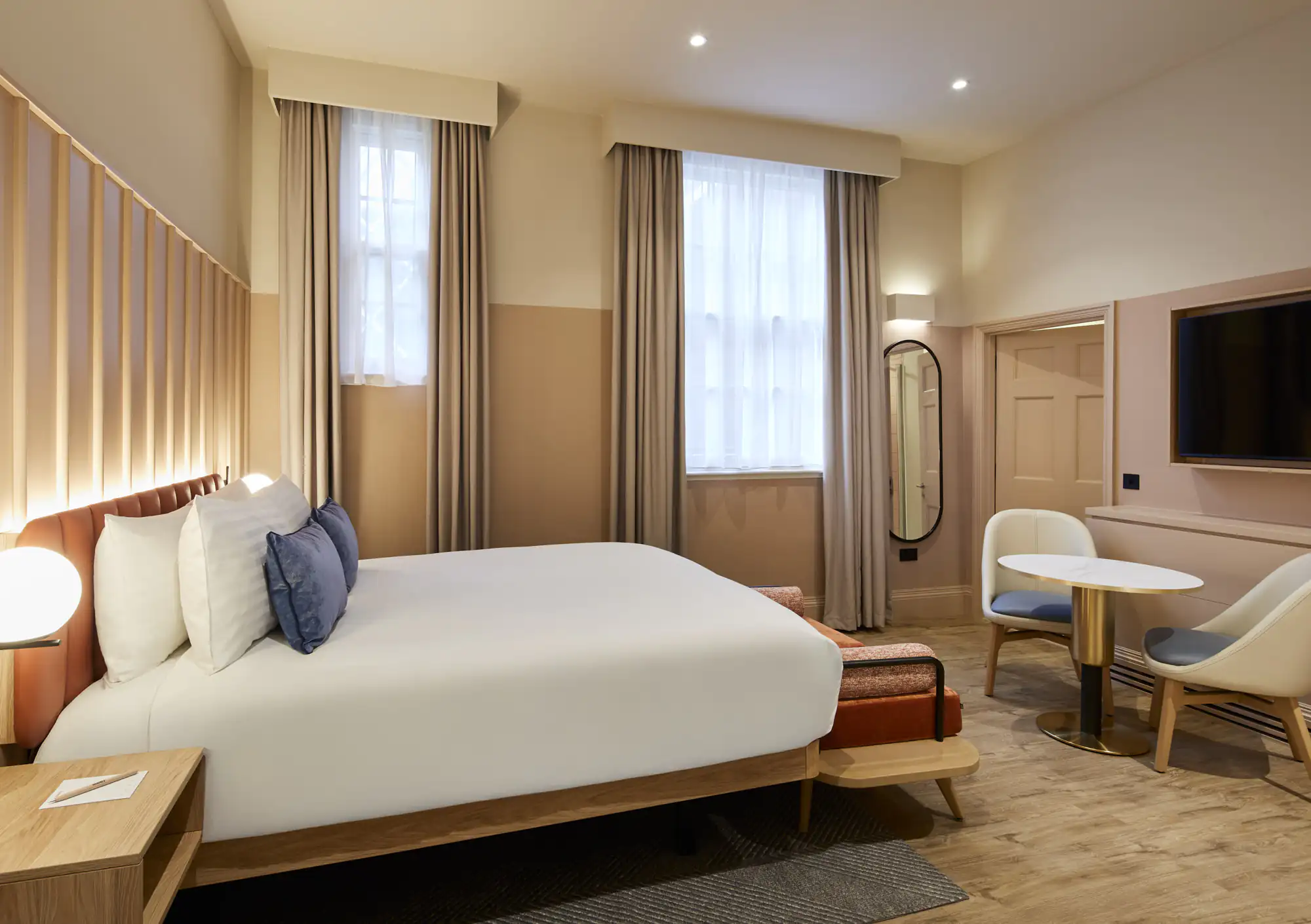 Inviting studio at master Cannon London with a large bed, stylish seating area, soft curtains, and a flat-screen TV for a relaxing stay.