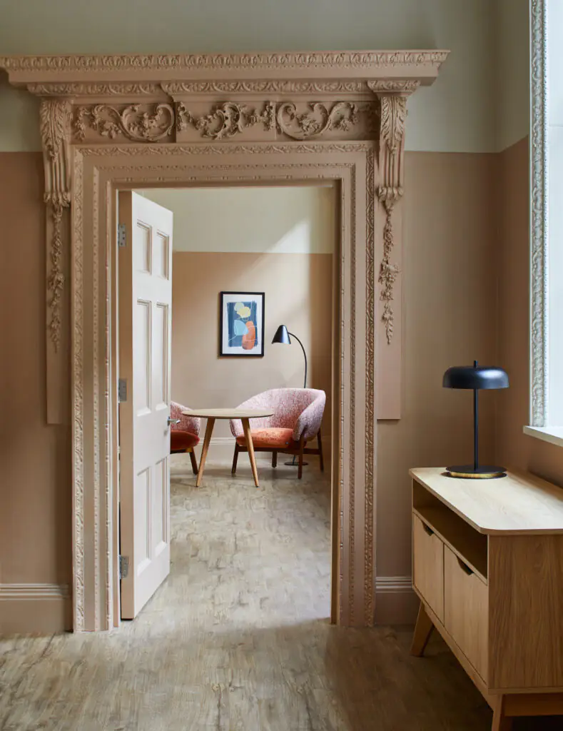Interior view through an ornate, carved doorway at master Cannon London apartments, showcasing refined furnishings and soft, modern lighting.