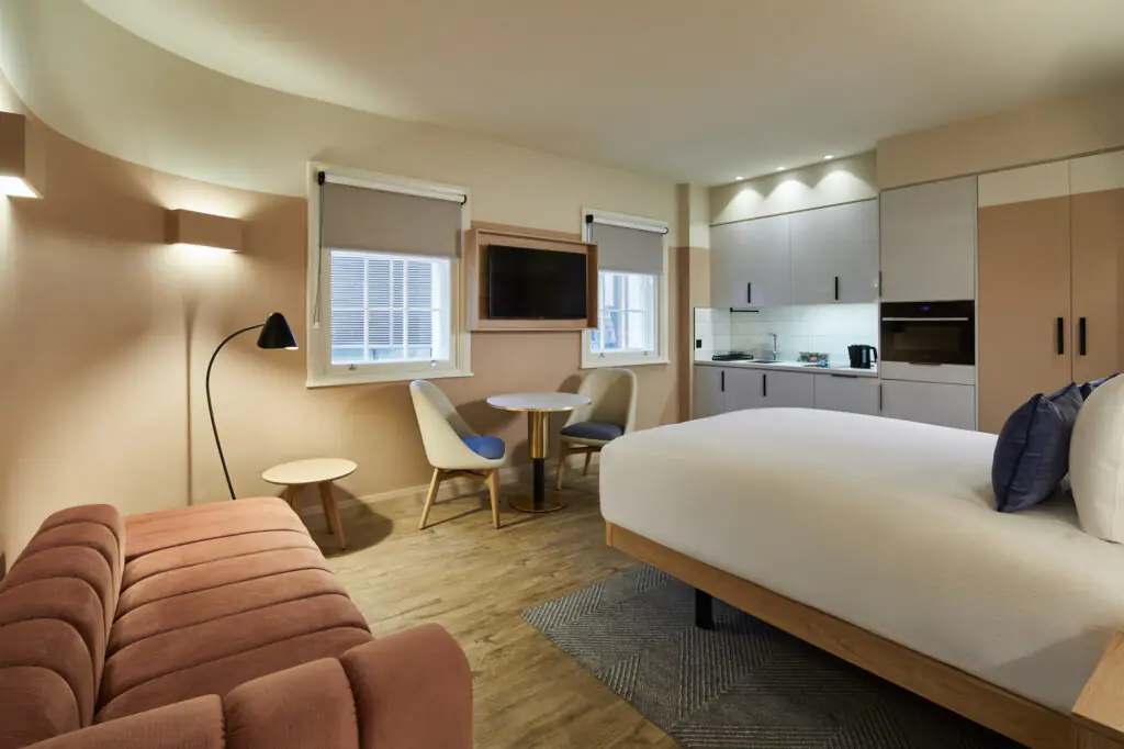 Open-plan studio with sofa bed at master Cannon London featuring sleeping and living areas, kitchen, and a cozy round dining table.