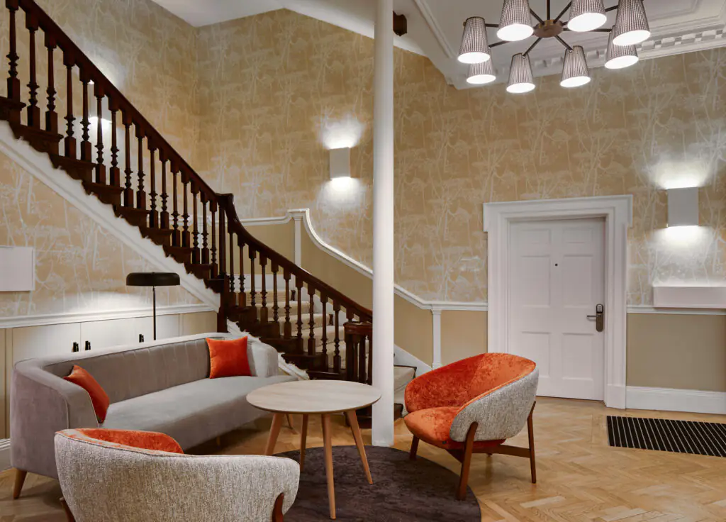 Sophisticated lobby area at master Cannon London apartments with a stylish seating arrangement, contemporary decor, and a wooden staircase leading upstairs