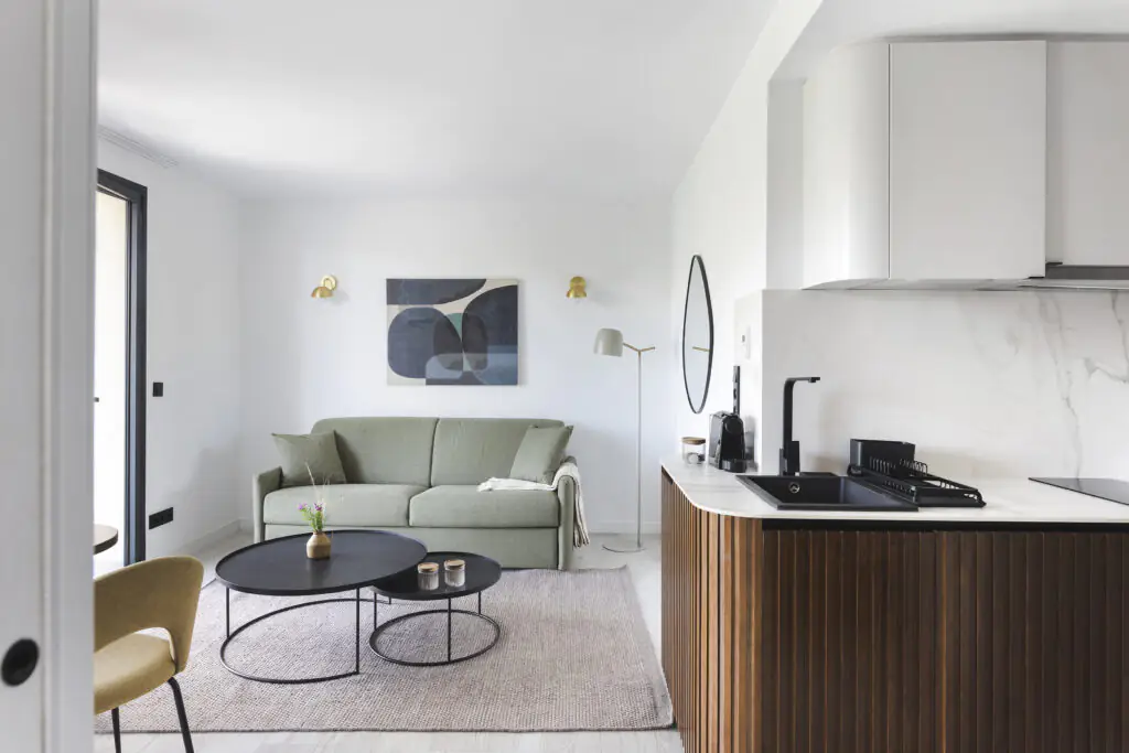 Contemporary living space at master La Rambla Barcelona with sofa, round coffee tables, and fully equipped kitchen.