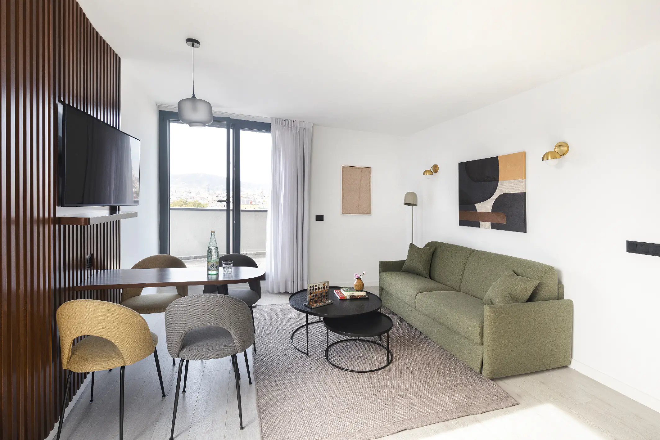 Stylish penthouse living and dining space with large TV, modern chairs, and floor-to-ceiling windows showcasing Barcelona’s skyline.