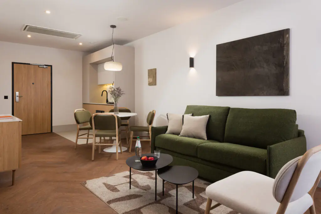 Open-plan apartment living space at master Wola Serviced Apartments with seating area and dining table